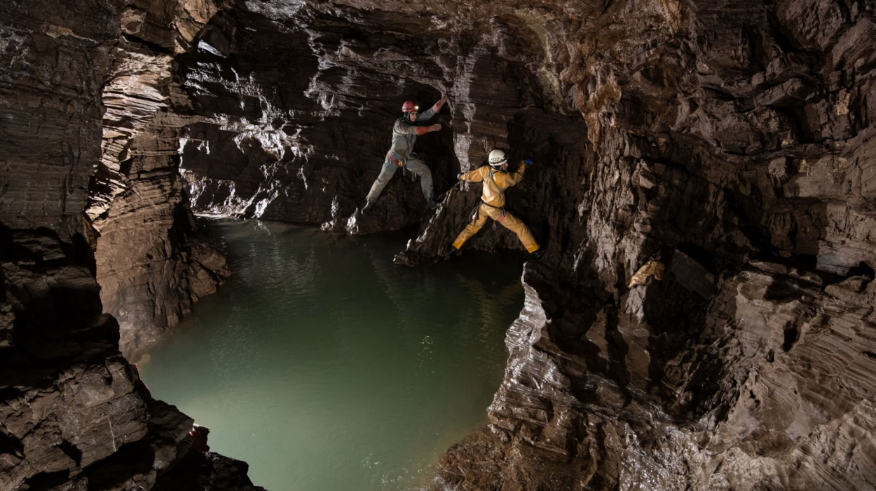 Cavers climb around a deep pool of water in one of the Veryovkina cave's side passages. | National Geographic