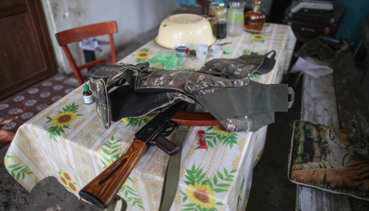 A bulletproof vest and an assault rifle are on the table in the yard of a house in Karabakh.