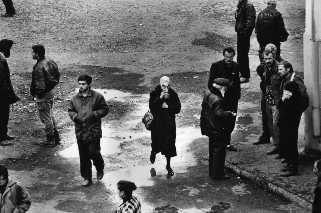 November 1993, Abkhazia. The reburial of around 120 Abkhaz soldiers who had been killed 6 months earlier in a Georgian ambush. After the takeover of Abkhazia by the Abkhaz forces, they exhumated the bodies and famillies came to indentify them. A woman wearing a gas mask because of the smell. Photo Credit & Caption: Thomas Dworzak