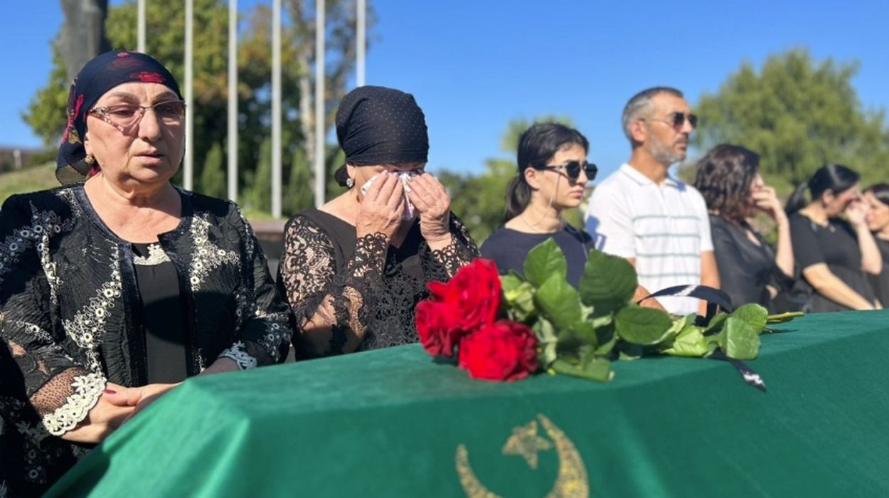 Family members of Arsen Efendiev stand solemnly beside his coffin.